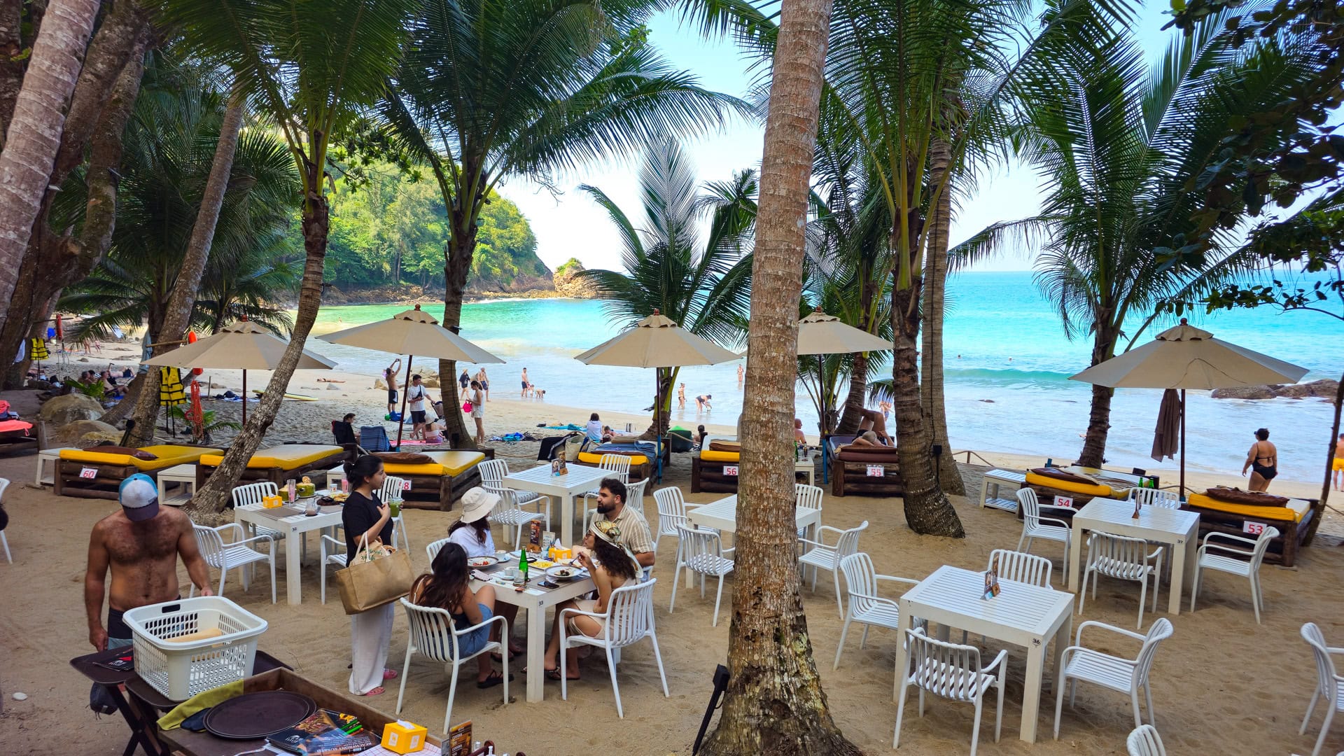 Tables and loungers under palm trees at Banana Beach Phuket beachfront restaurant.