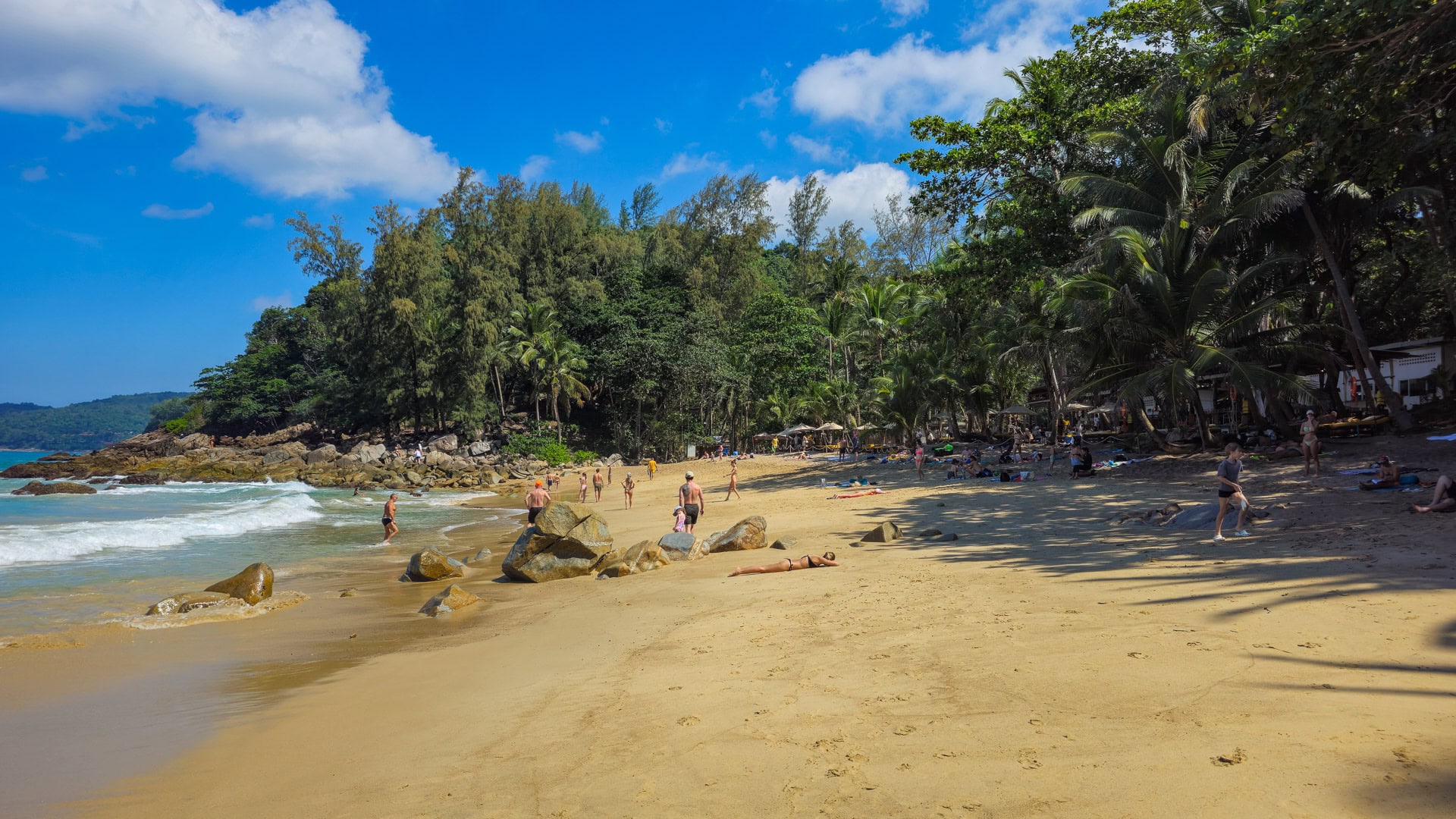 Sandy shoreline with scattered rocks and small surf on Banana Beach Phuket.