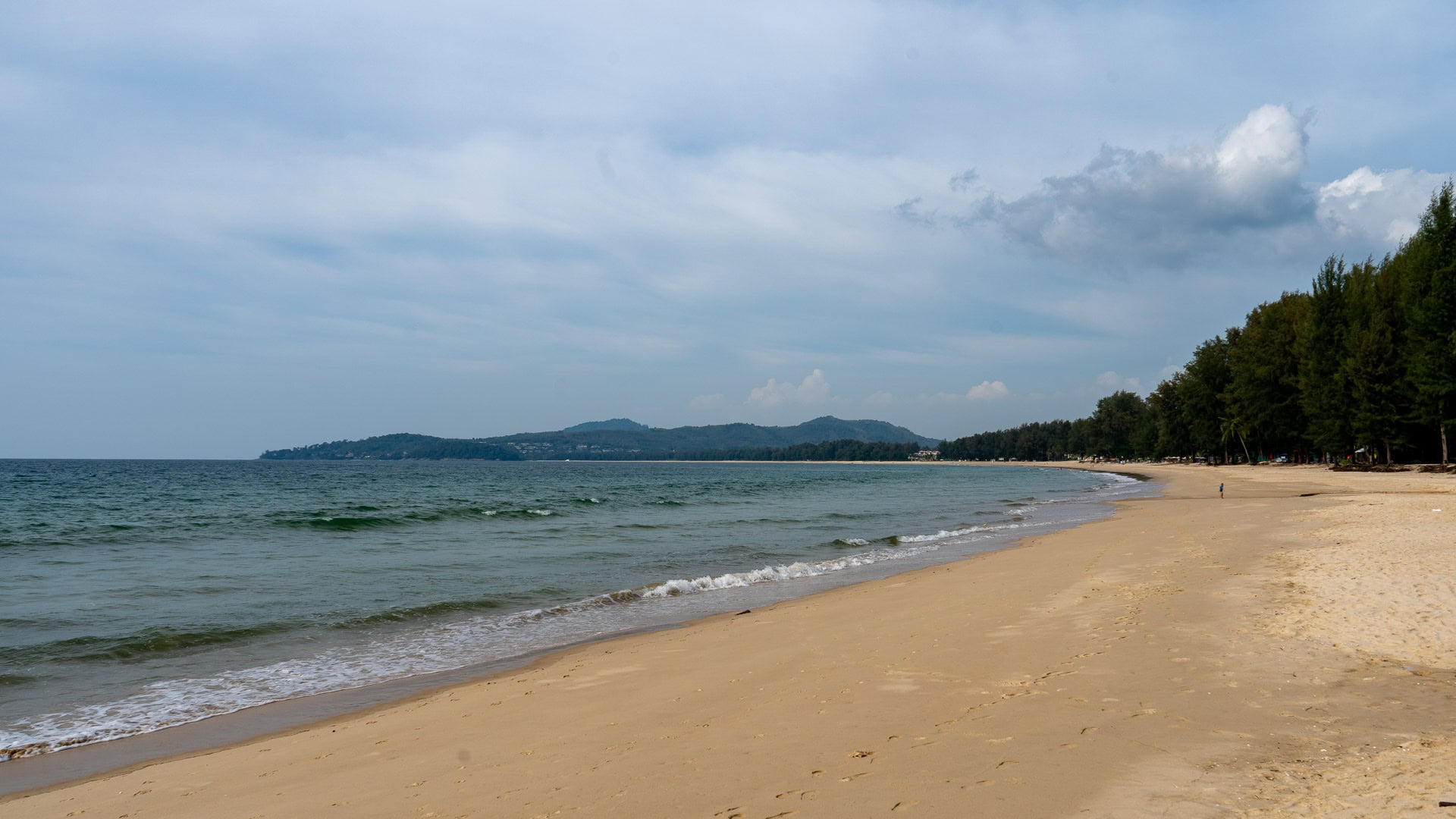 Northern section of Bang Tao Beach with light surf and open sand.