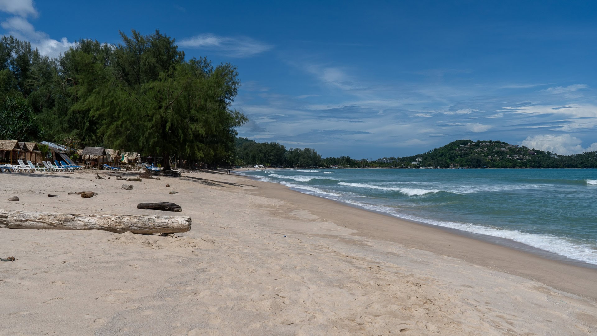 Shoreline view toward the hills with light surf and swimmers near the waterline.