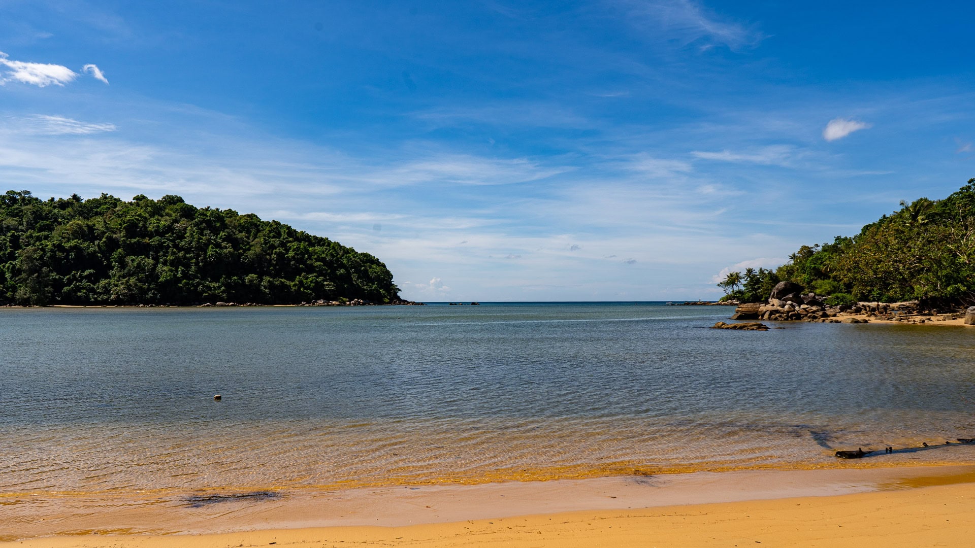 Calm lagoon water bordered by green hillside and quiet shoreline.