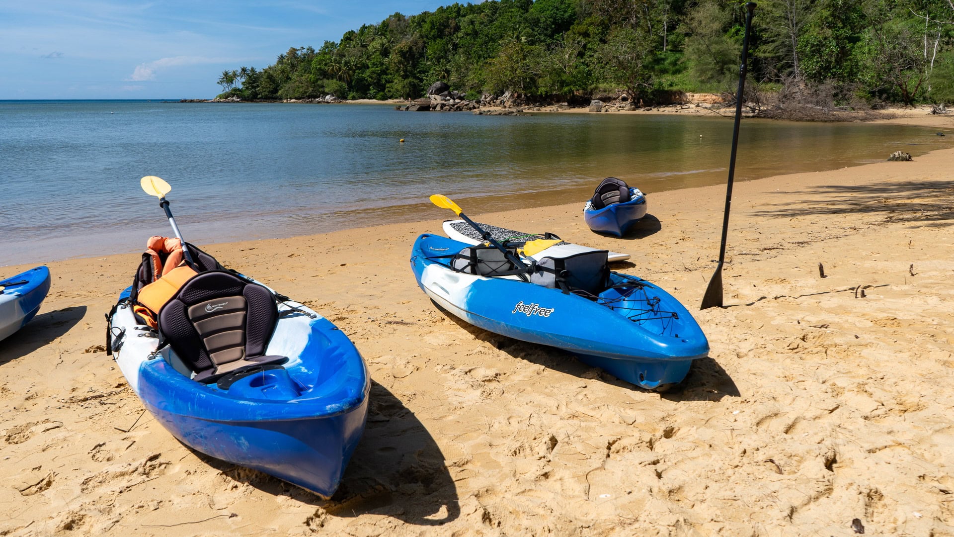 Close view of kayaks ready for launch on sandy beach near calm water.