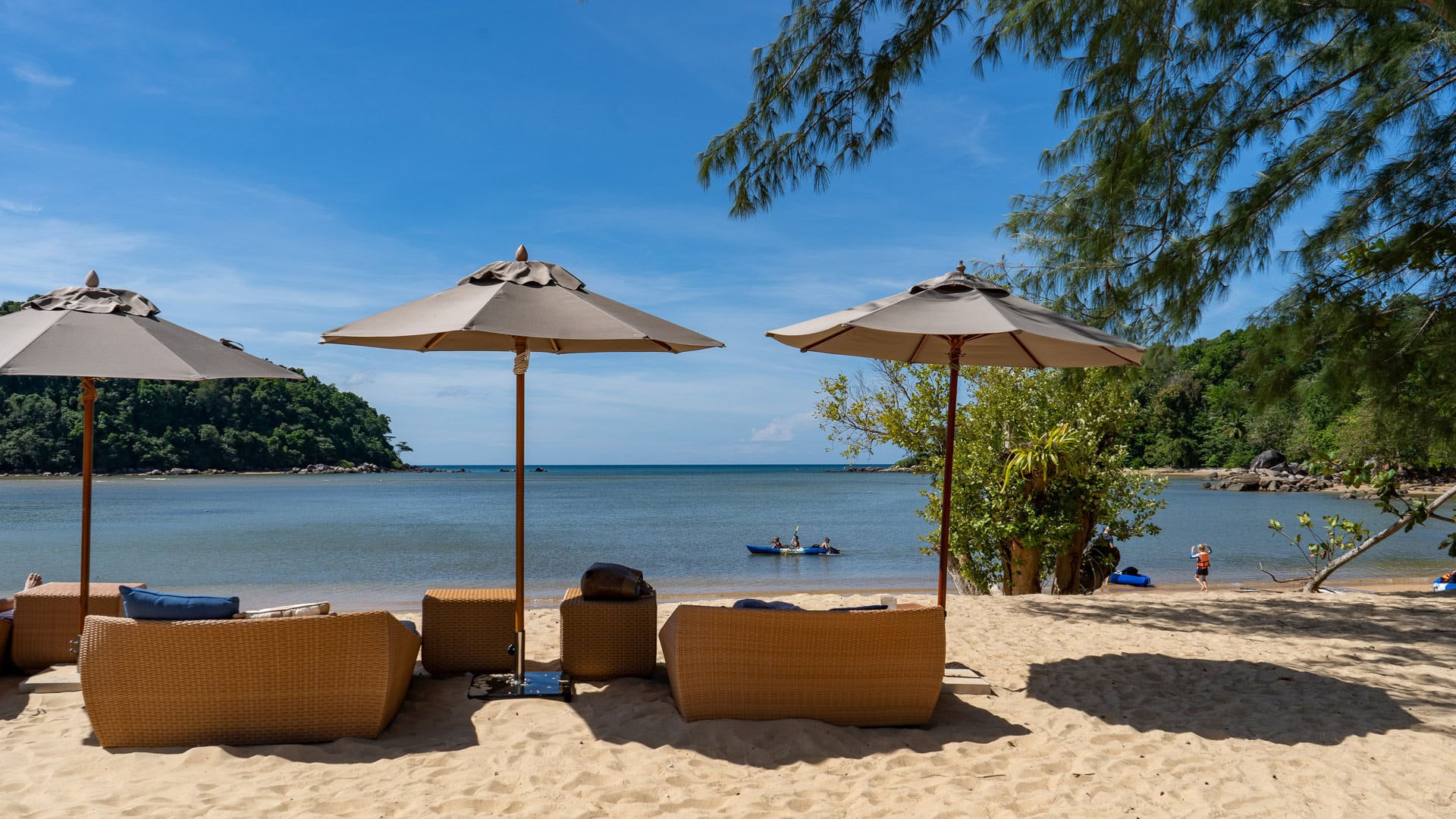 Wicker loungers and umbrellas facing the quiet sea near the headland.