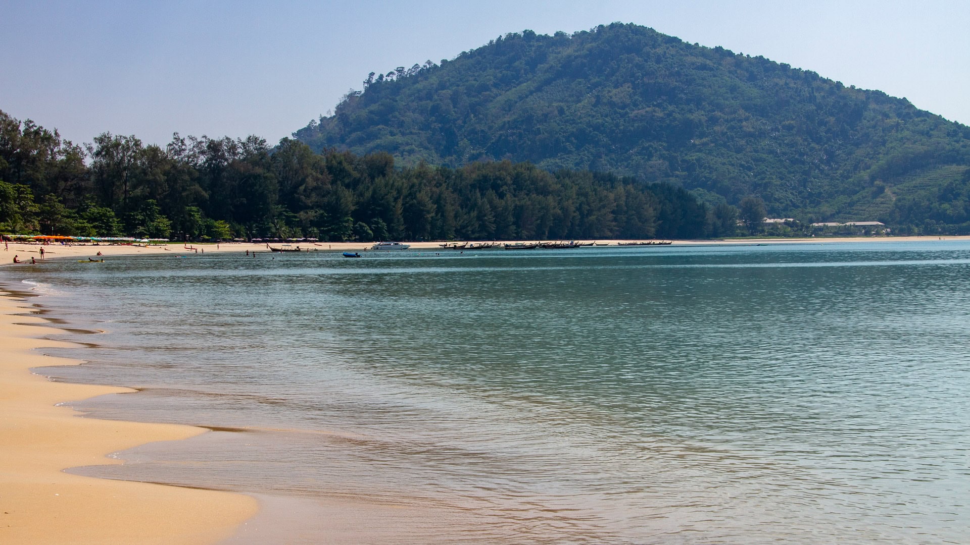 Shallow sea over sandbars at Nai Yang Beach Phuket during low tide with distant coastline.