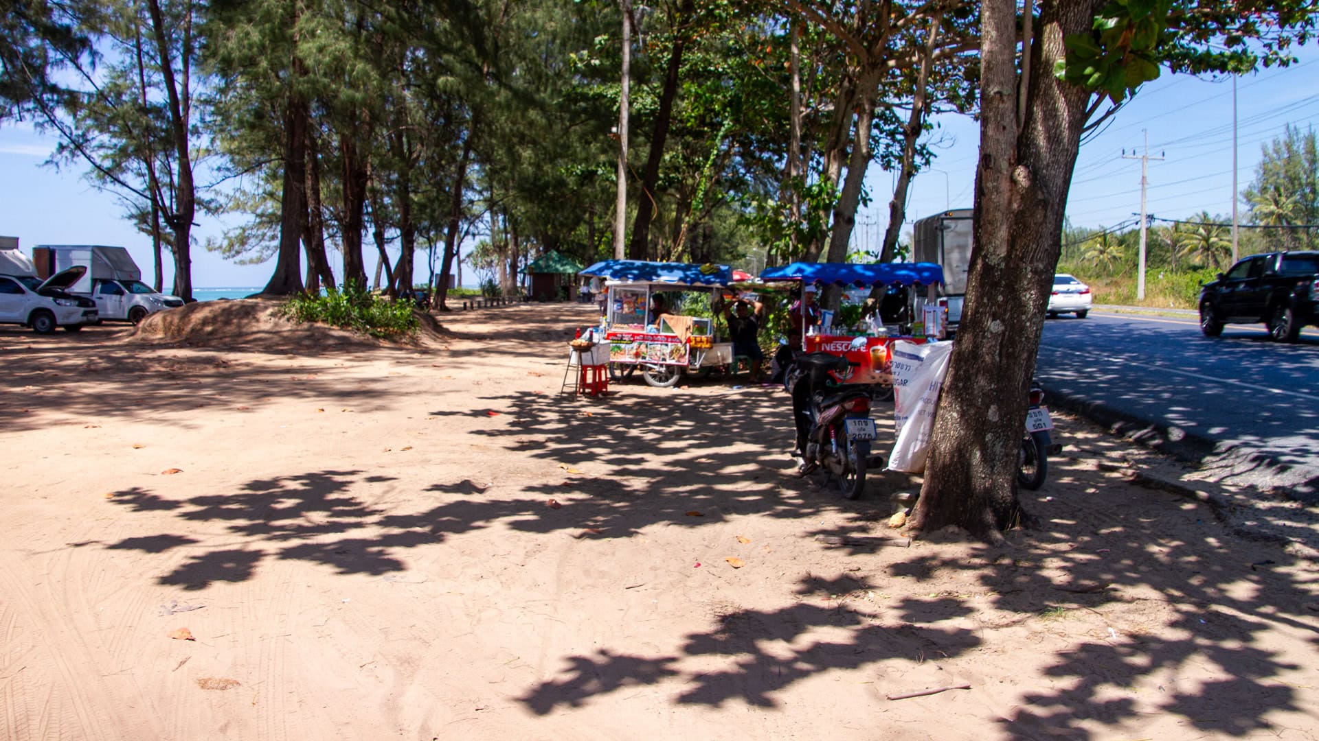 Sai Kaew Beach Phuket roadside vendors under tree shade beside Route 402.