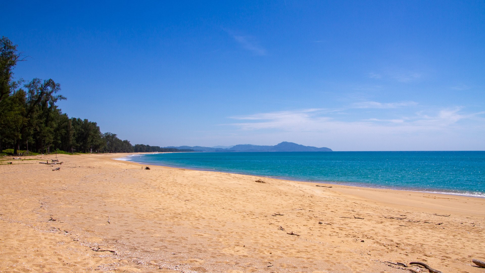 Sai Kaew Beach Phuket wide view of golden sand and turquoise water with Phang Nga mainland on the horizon.