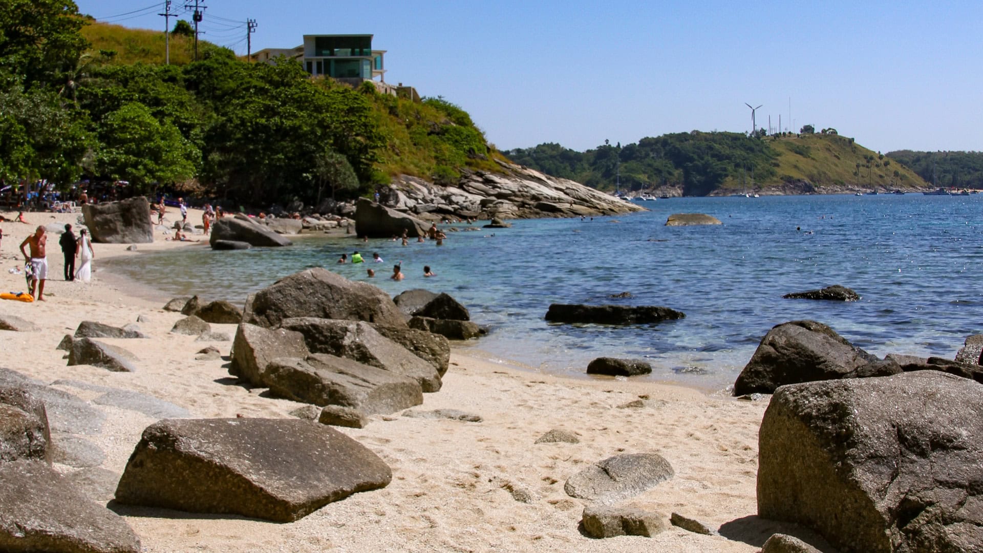 Ao Sane Beach Phuket granite rocks along the waterline with swimmers nearby