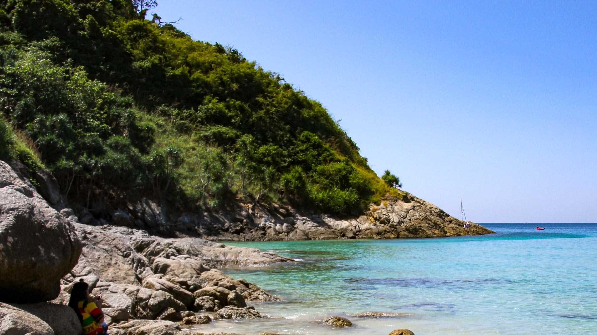 Ao Sane Beach Phuket small bay with rocks, swimmers, and hillside in background
