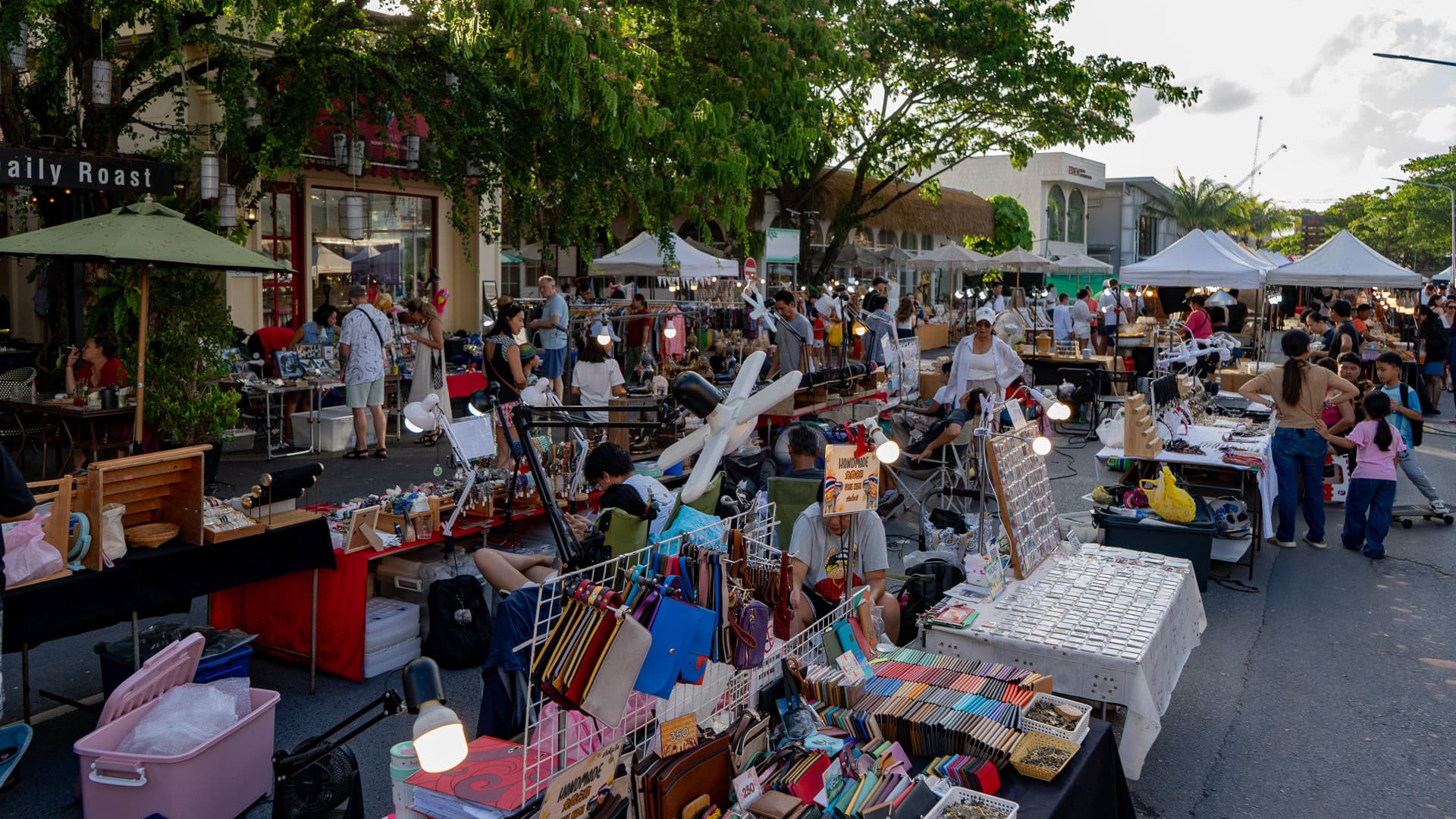 Fun Friday Boat Avenue Market Phuket with a wide aisle of market stalls, tables displaying goods, and people browsing and walking between the stalls