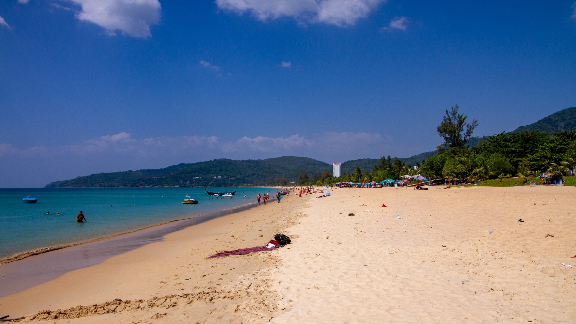 Long shoreline view at Karon Beach Phuket with calm water and hills