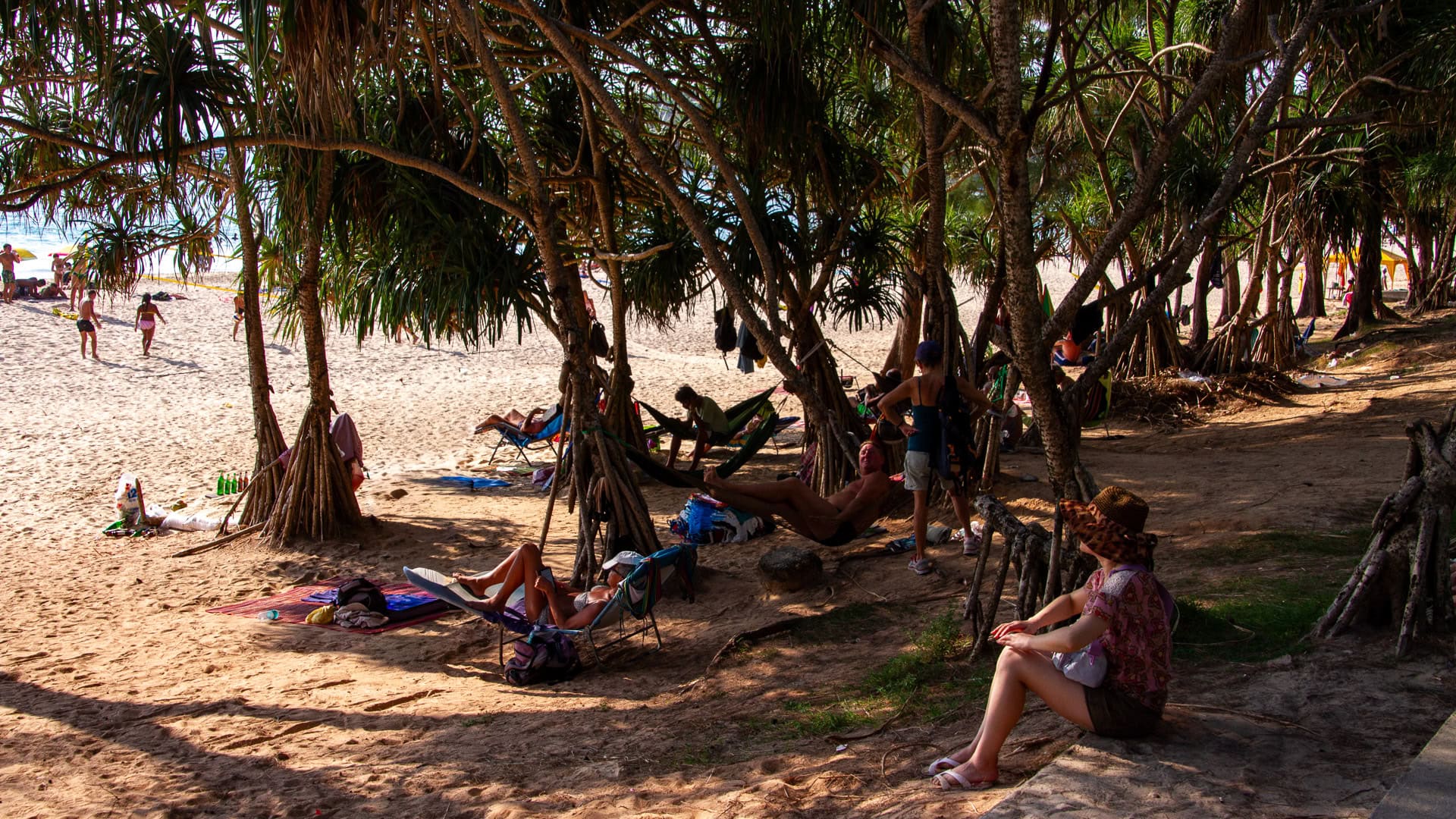 Kata Beach Phuket shaded area with trees, hammocks, and people resting on sand
