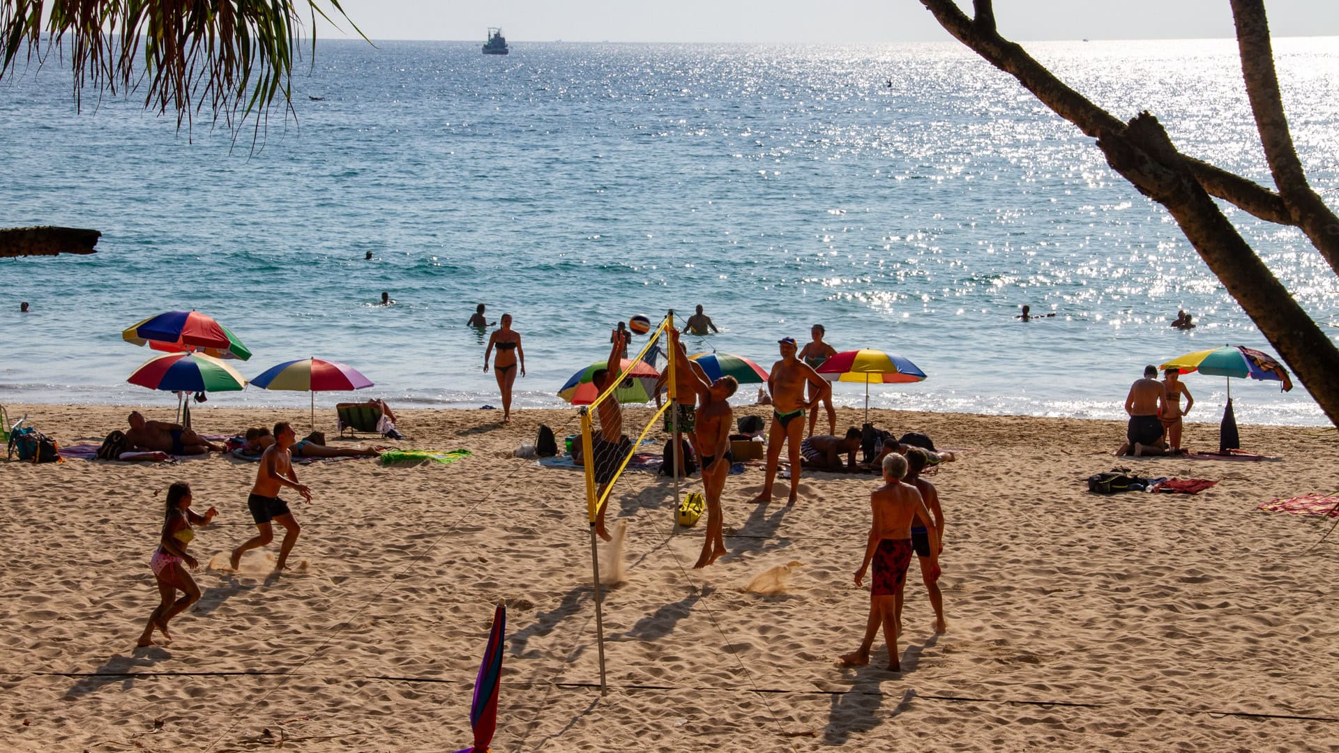 Kata Beach Phuket beach volleyball game with umbrellas and swimmers in the background