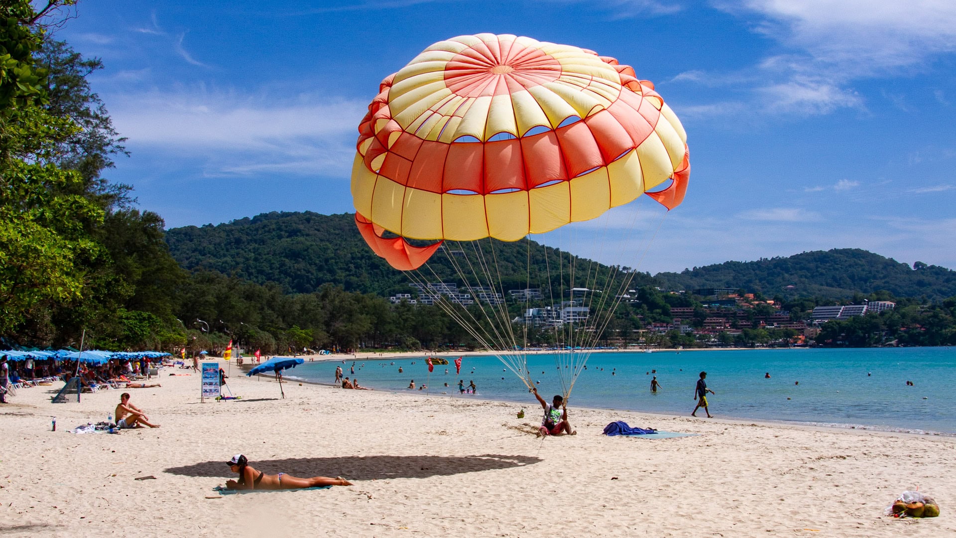 Kata Beach Phuket parasailing activity on the sand with parachute canopy and beach users