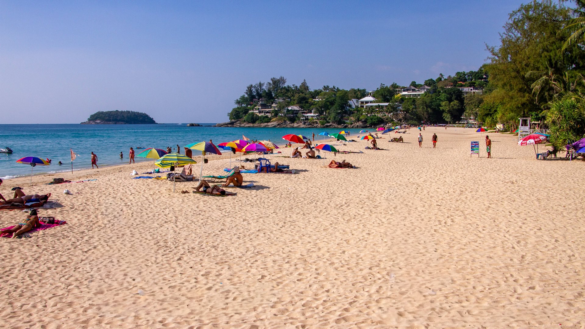 Kata Noi Beach Phuket wide sandy shoreline with scattered umbrellas and people sunbathing