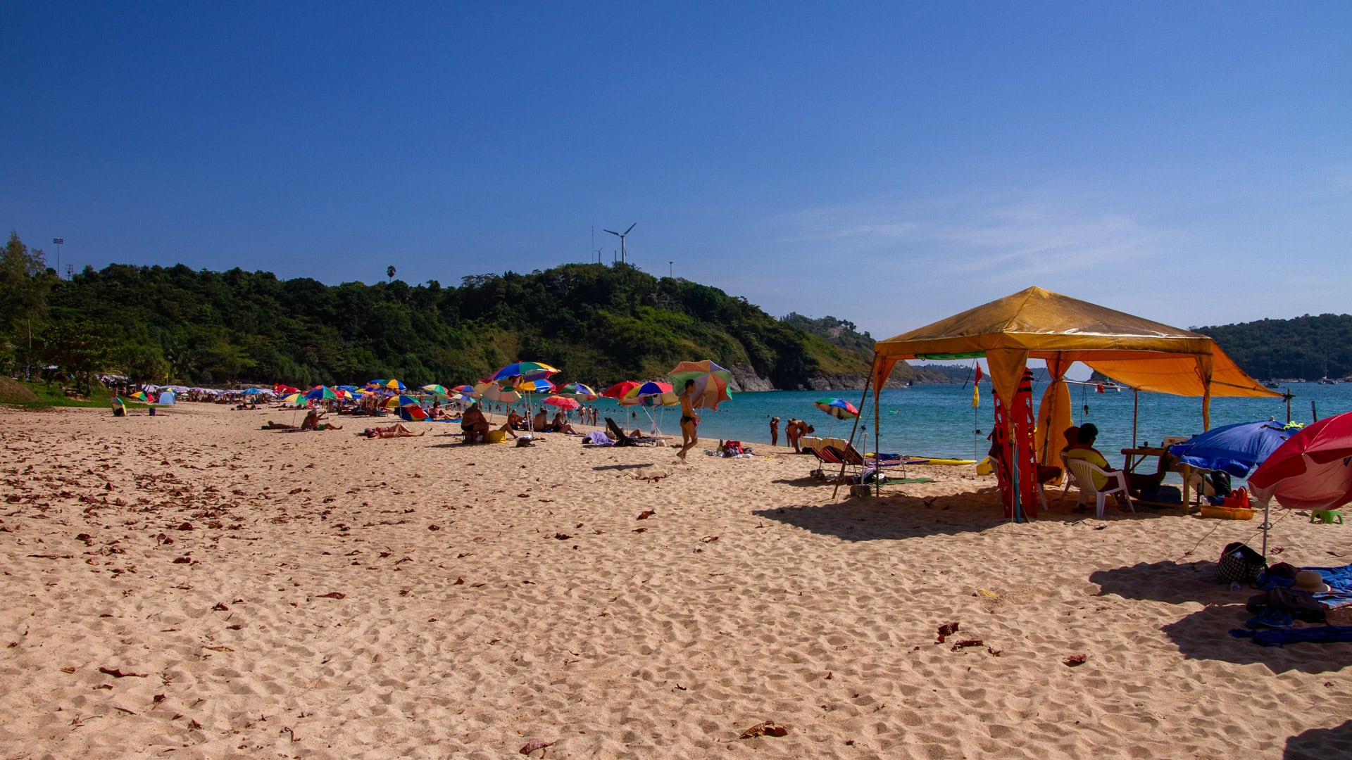 Nai Harn Beach Phuket sandy beach with colorful umbrellas and shaded seating area