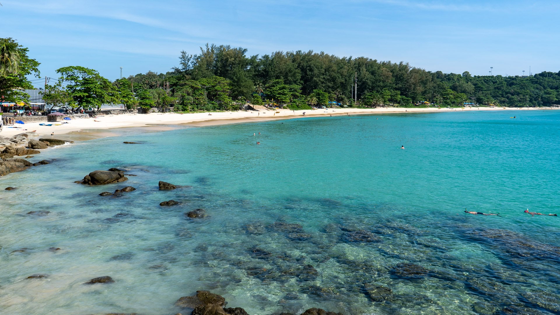 Nai Harn Beach Phuket clear shallow water near rocky shoreline and tree cover