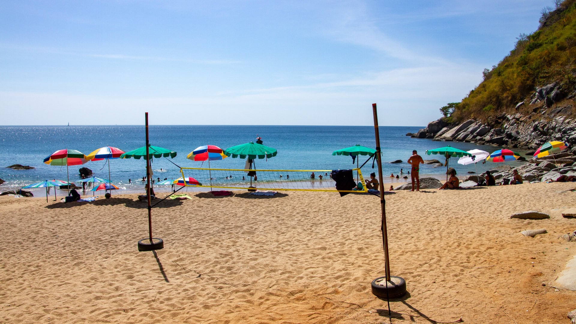 Nui Beach Phuket volleyball net on sand with umbrellas and swimmers offshore