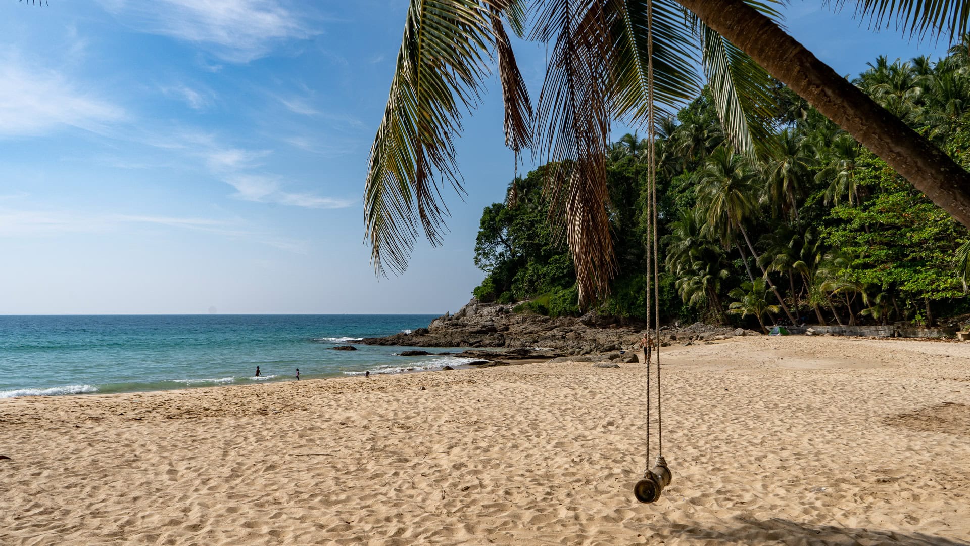 Long open section of sand with calm sea and sparse umbrellas.