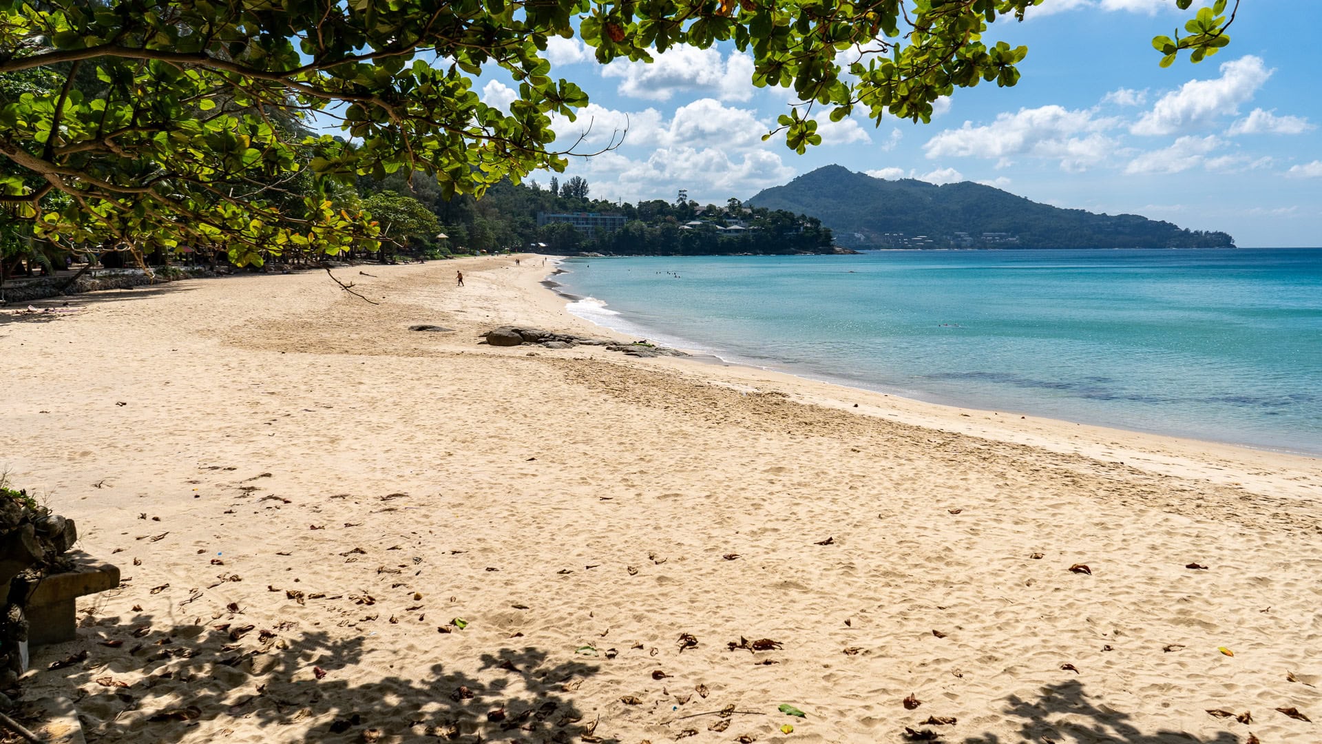 Broad sandy stretch with gentle waves along the west-facing bay.