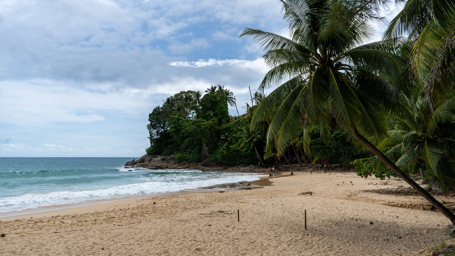 Palm-backed southern corner with rocks and light surf.