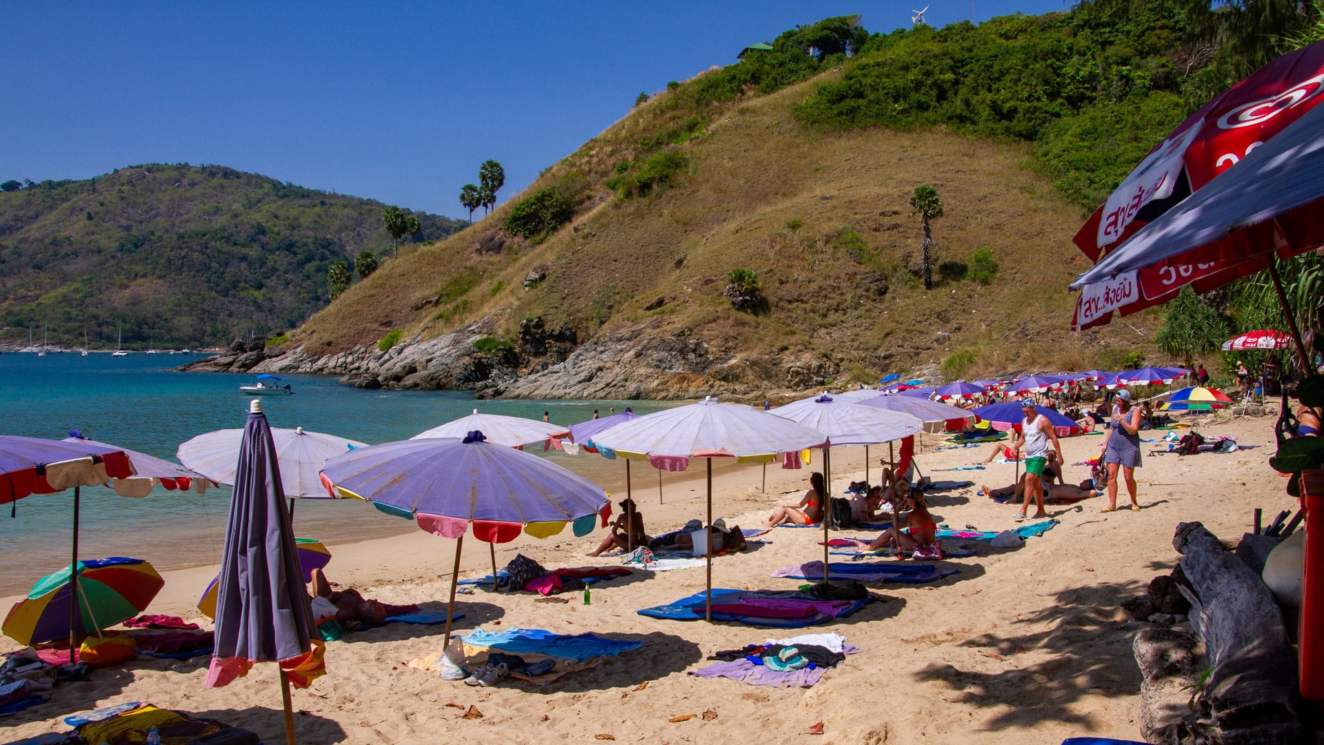 Yanui Beach Phuket sandy shoreline with umbrellas and hillside backdrop