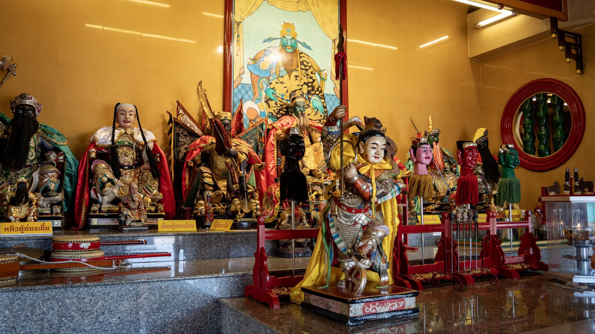 A side-angle view of the main altar shows deity figures, ceremonial heads, a kneeling warrior statue, and a round red-framed window in the wall.