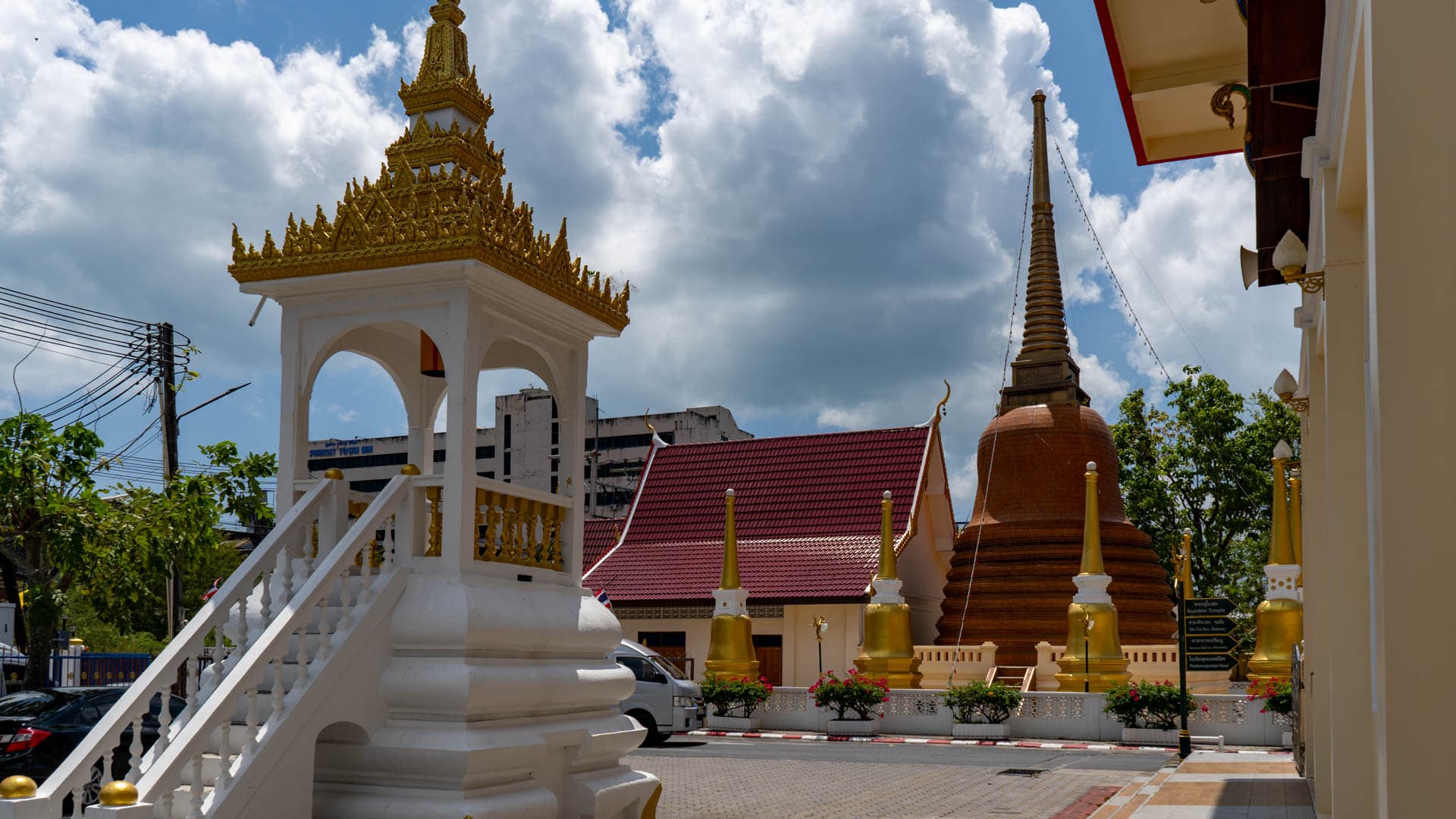 White stair temple bell tower beside brown chedi at Wat Mongkolnimit temple