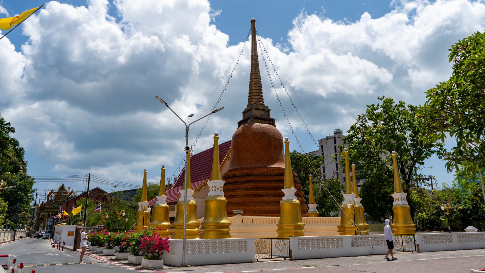 Brown chedi with gilded spires and visitors at Wat Mongkolnimit