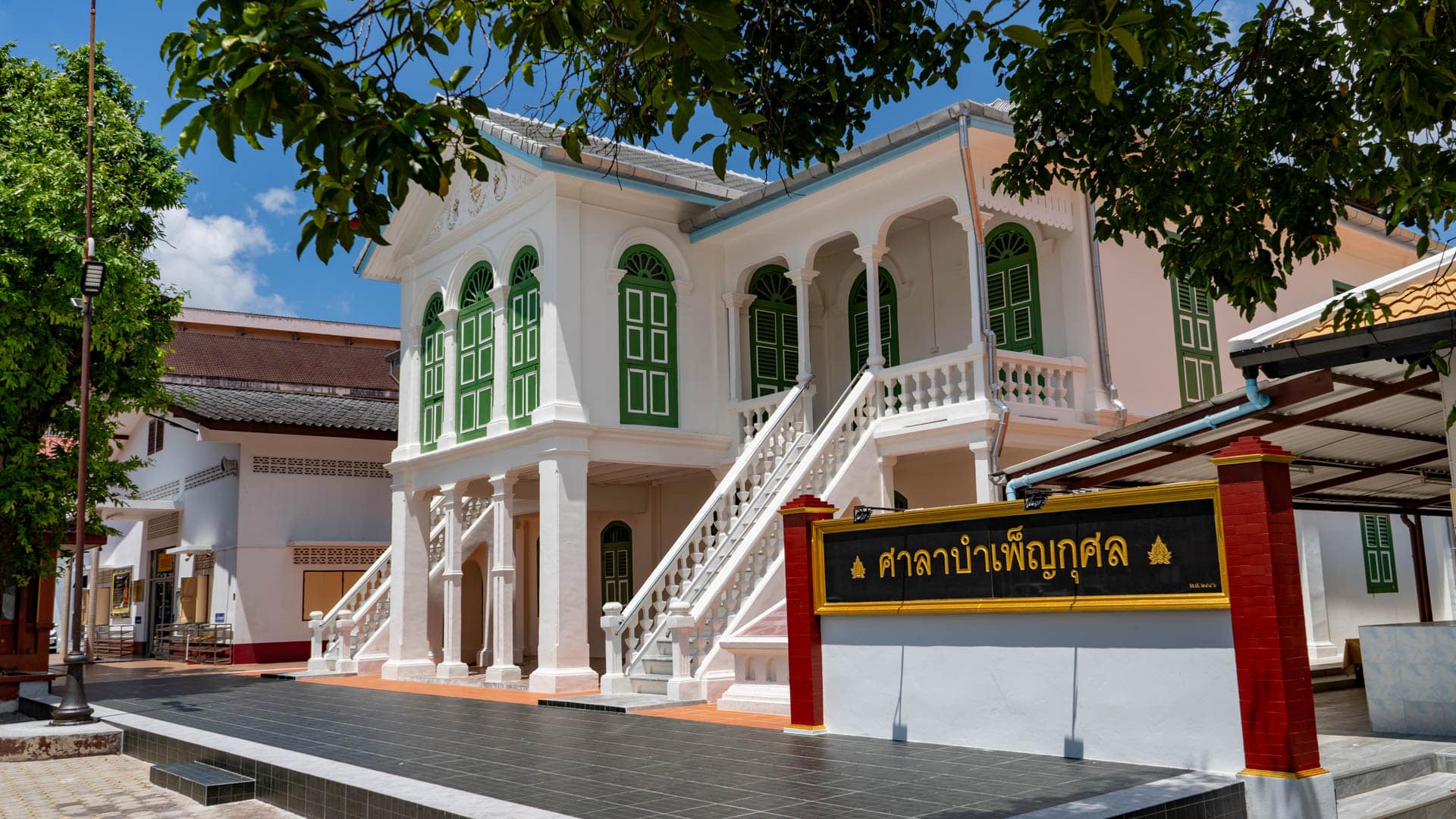 Black Thai sign in front of colonial-style building at Wat Mongkolnimit